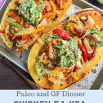 two spaghetti squash halves stuffed chicken fajitas and guacamole on a silver baking sheet.