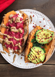 Two stuffed sweet potaotes with raspberry chia jam, almond butter, spinach, and avocado