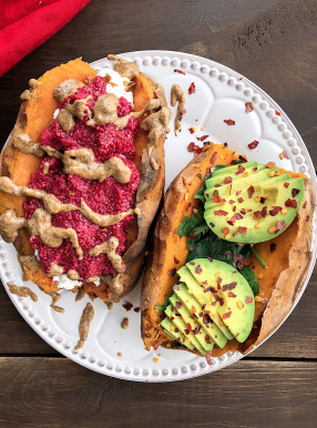 Two stuffed sweet potaotes with raspberry chia jam, almond butter, spinach, and avocado