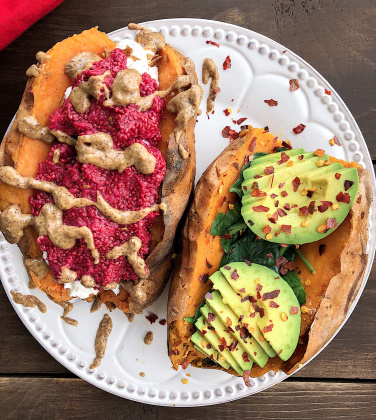 Two stuffed sweet potaotes with raspberry chia jam, almond butter, spinach, and avocado