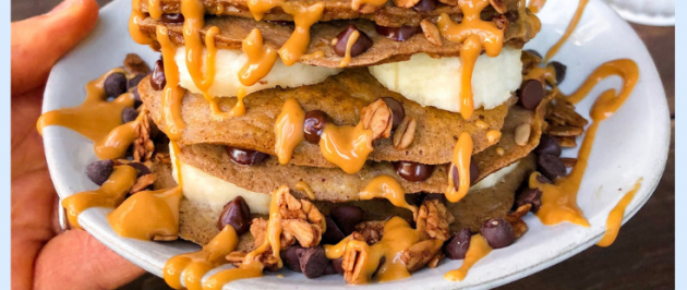 Paleo pancakes with bananas, chocolate chips, peanut butter drizzle on a white plate