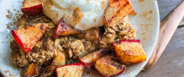 Slice of baked oatmeal topped with yogurt, cinnamon apples on a white plate