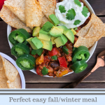 Turkey chili in a bowl with tortilla chips, avocado, kefir, jalapanoes, on a brown background