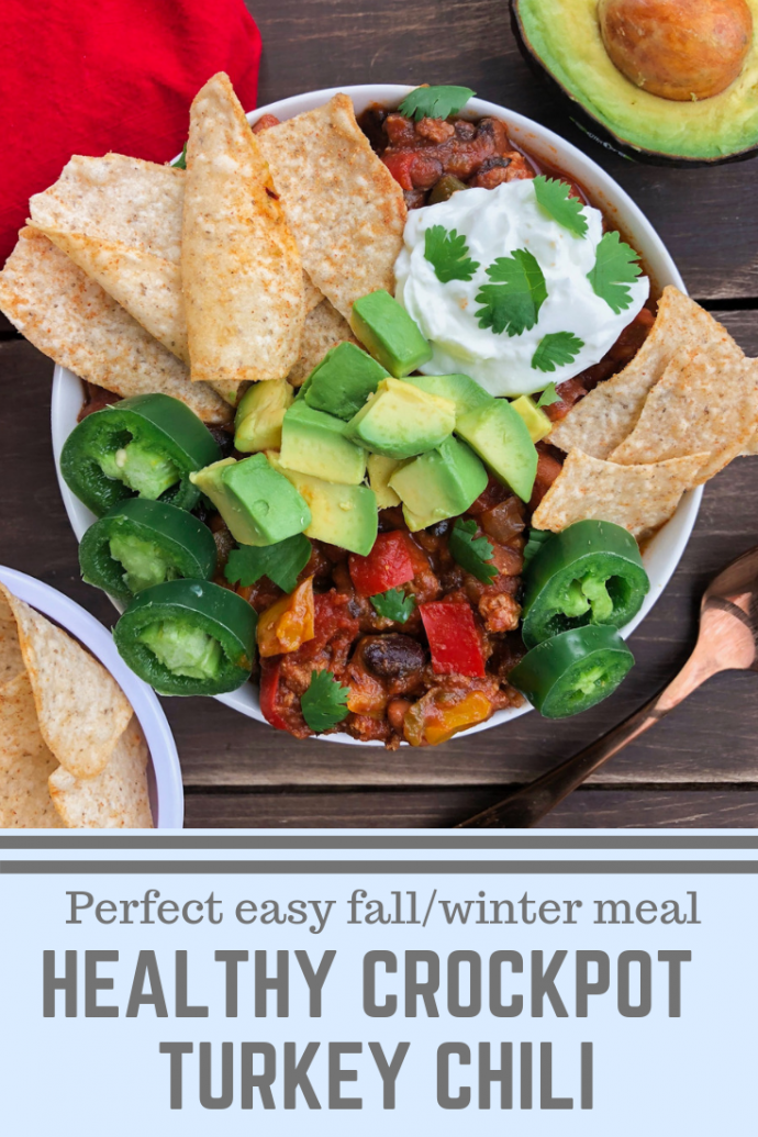 Turkey chili in a bowl with tortilla chips, avocado, kefir, jalapanoes, on a brown background 