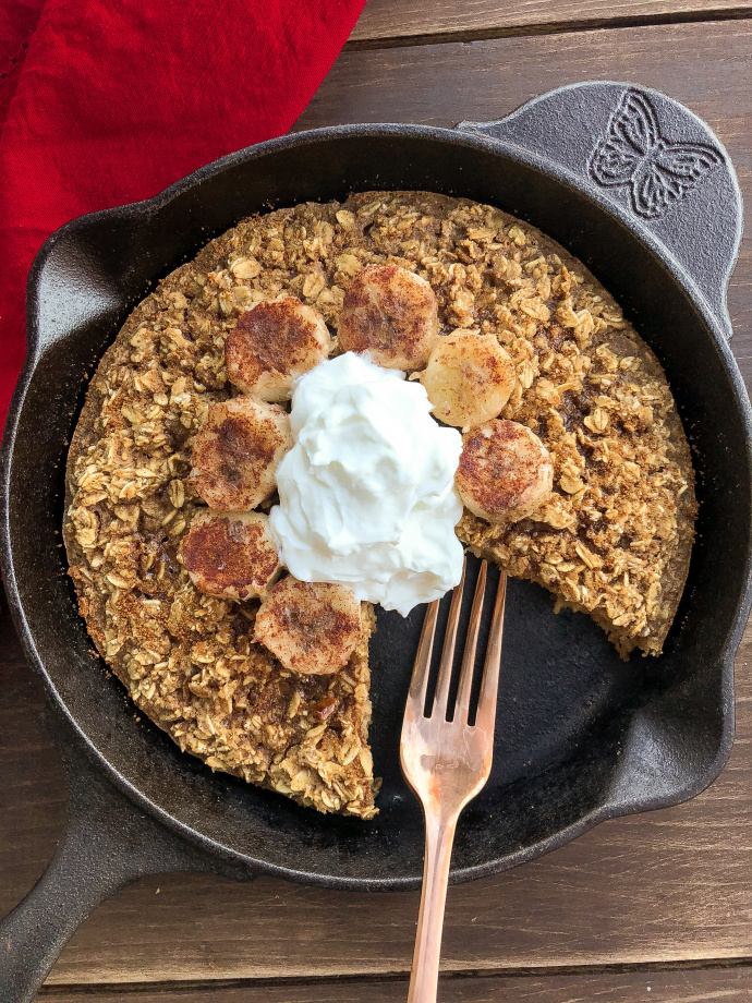 Baked Oatmeal topped with yogurt and bananas in a black skillet. 