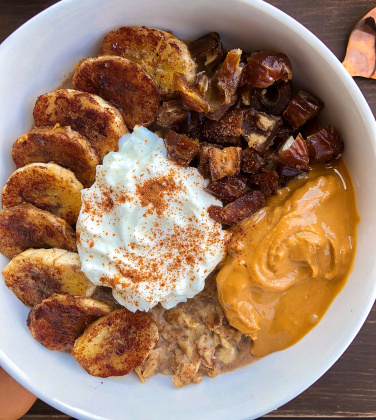 oatmeal with peanut butter, kefir, dates, and bananas on top in a white bowl