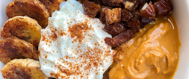 oatmeal with peanut butter, kefir, dates, and bananas on top in a white bowl