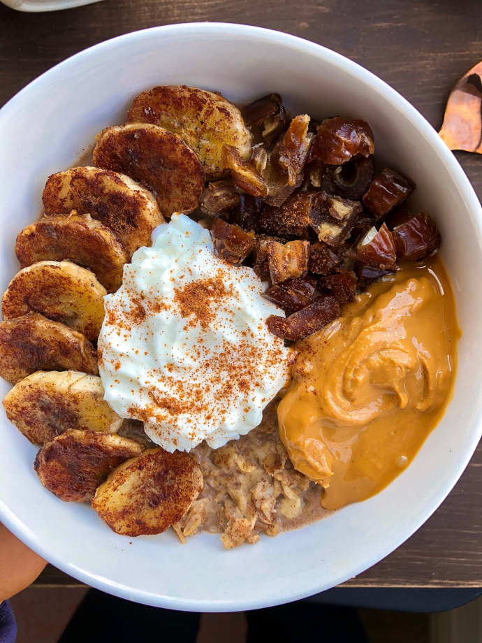 oatmeal with peanut butter, kefir, dates, and bananas on top in a white bowl