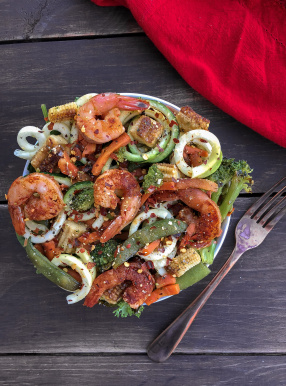 Shrimp with stir fry veggies and zucchini noodles on a wood background.