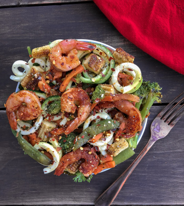 Shrimp with stir fry veggies and zucchini noodles on a wood background.