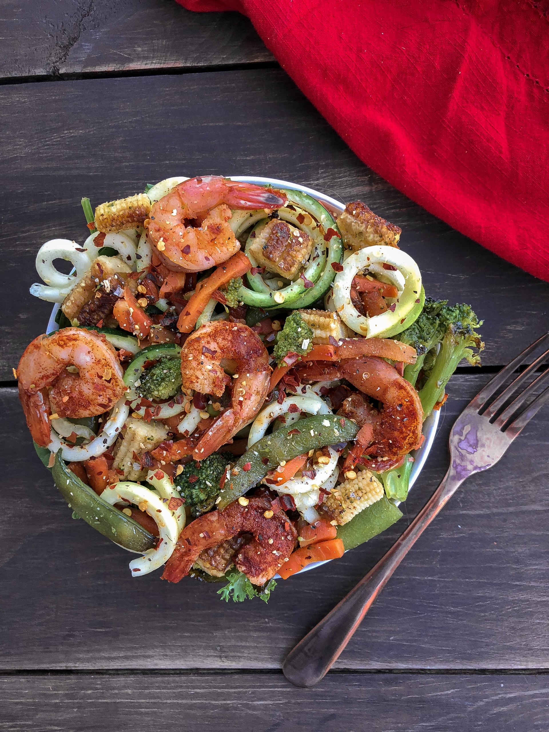 Shrimp with stir fry veggies and zucchini noodles on a wood background.