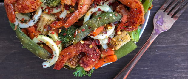 Shrimp with stir fry veggies and zucchini noodles on a wood background.