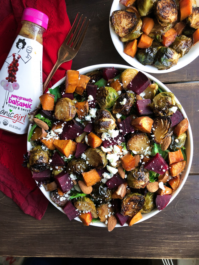 Roasted beet, brussels, sweet potatoes, feta salad in a white bowl on a brown board