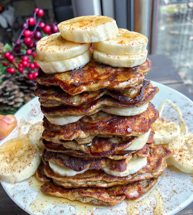 paleo banana pancakes on a white plate with bananas and honey on top.