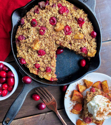 gluten free baked oatmeal with yogurt on top in a cast iron skillet on a wood board .