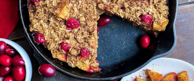 gluten free baked oatmeal with yogurt on top in a cast iron skillet on a wood board .