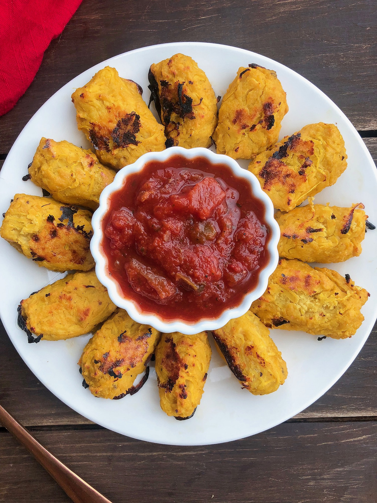 spaghetti squash tater tots on a white plate with salsa in a cup in the middle