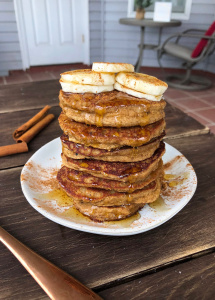 snickerdoodle paleo pancakes with bananas and honey on a white plate