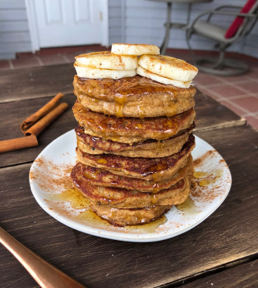 snickerdoodle paleo pancakes with bananas and honey on a white plate