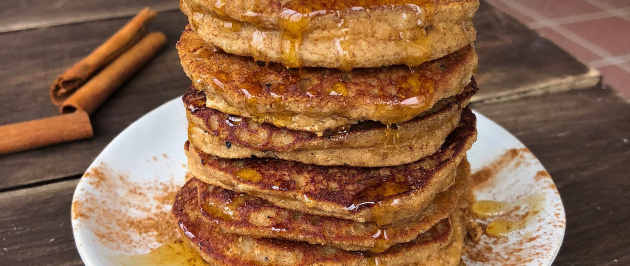 snickerdoodle paleo pancakes with bananas and honey on a white plate