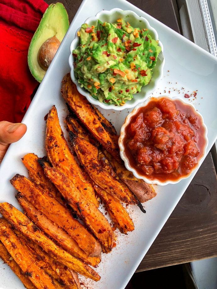 Spicy sweet potato fries on a white plate with salsa and avocado.