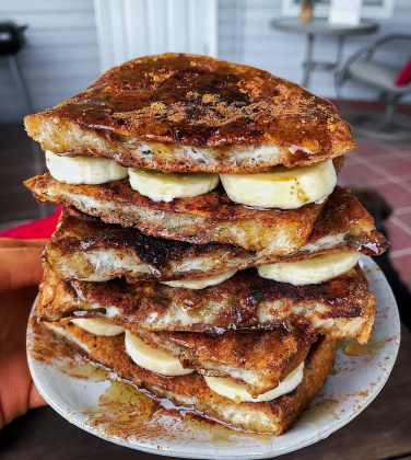 french toast with bananas on a white plate on a brown board