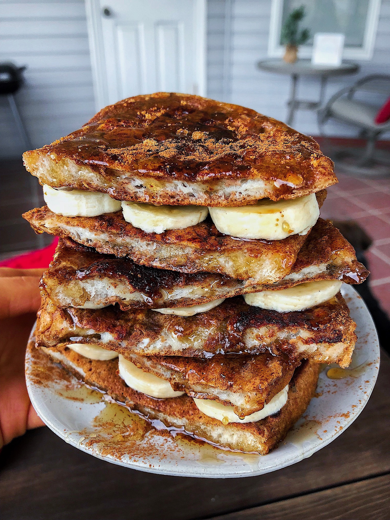 french toast with bananas on a white plate on a brown board