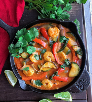 Coconut shrimp curry with veggies in a black cast iron skillet