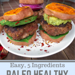 Grass fed burger in between sweet potato buns on a white plate with red pepper flakes.