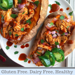 Two sweet potatoes stuffed with bbq chicken on a white plate