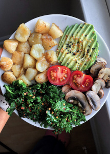 cauliflower gnocchi, avocado, tomato, sautéed mushrooms, and sautéed kale on a white plate