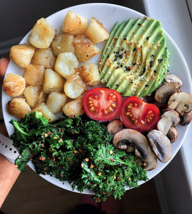 cauliflower gnocchi, avocado, tomato, sautéed mushrooms, and sautéed kale on a white plate