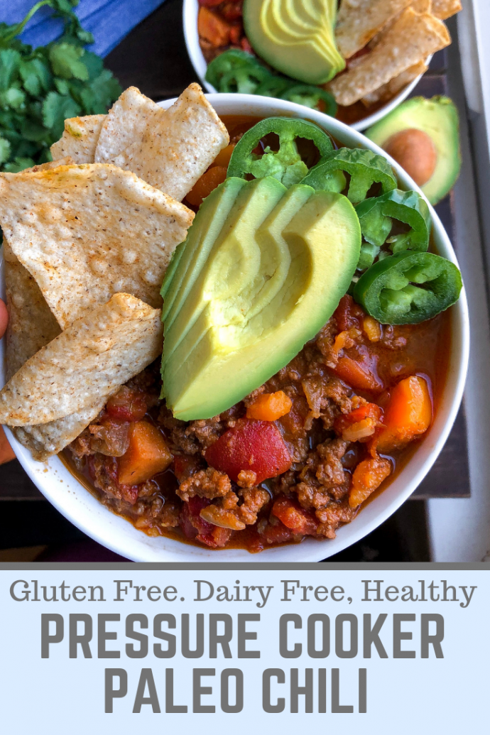 Paleo chili in a bowl with avocado, jalapenos, and tortilla chips in a white bowl.