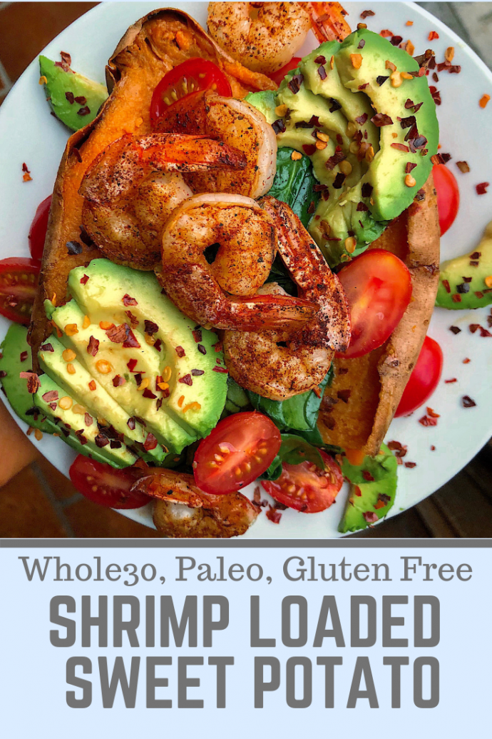 Shrimp, avocado, tomatoes, and spinach stuffed in a sweet potato on a white plate.