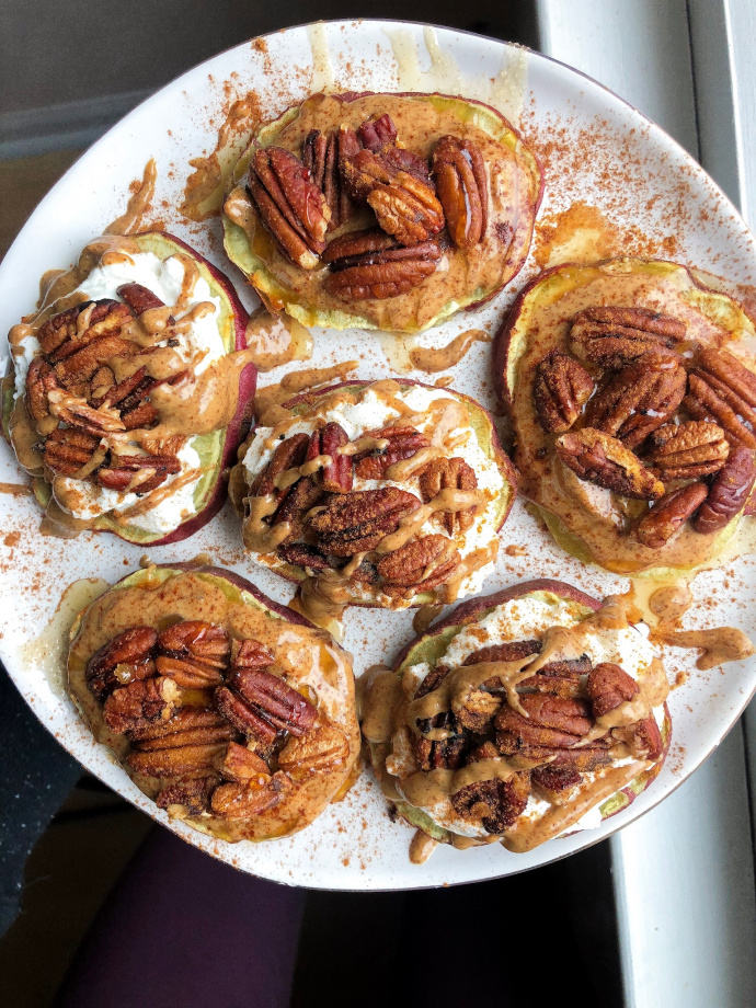 pecans, almond butter, yogurt, and cinnamon on sweet potatoes on a white plate