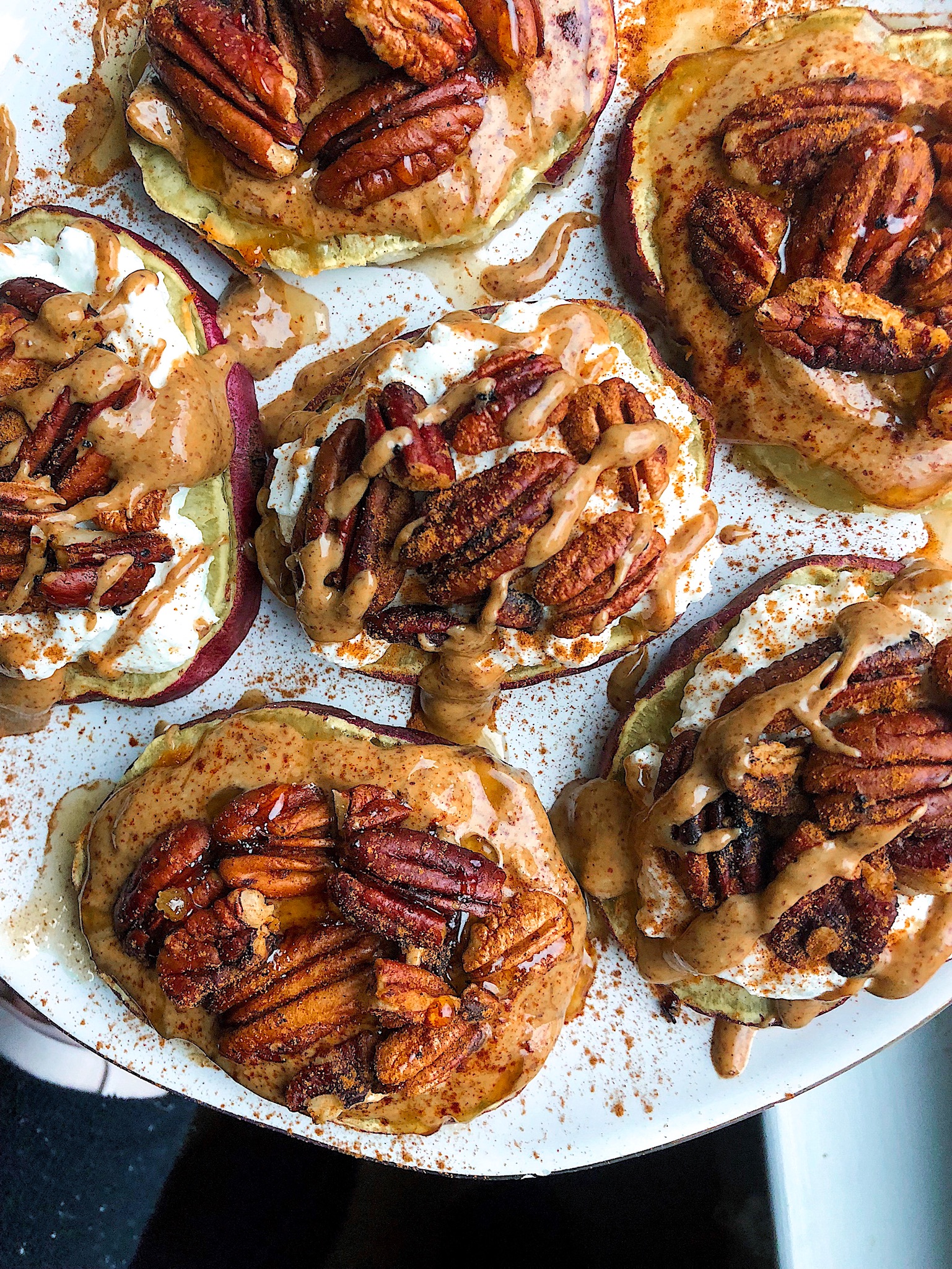 pecans, almond butter, yogurt, and cinnamon on sweet potatoes on a white plate