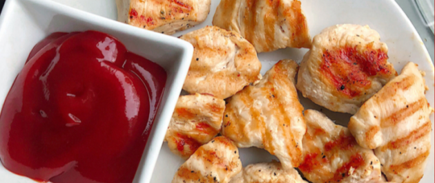 healthy grilled chicken nuggets on a white plate with ketchup