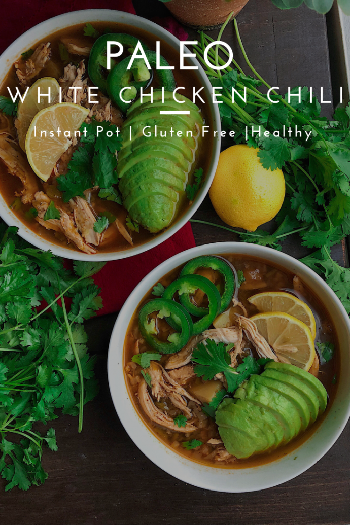 white chicken chili in a white bowl topped with avocado, jalapenos, and lemon.