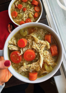 healthy chicken and rice soup with cauliflower rice and carrots in a white bowl