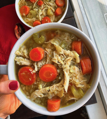 healthy chicken and rice soup with cauliflower rice and carrots in a white bowl