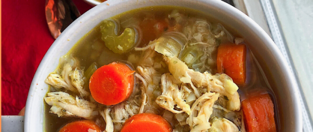 healthy chicken and rice soup with cauliflower rice and carrots in a white bowl