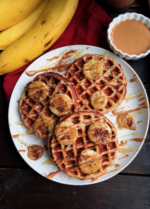 paleo waffles on a white plate with peanut butter and bananas on top