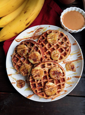 paleo waffles on a white plate with peanut butter and bananas on top