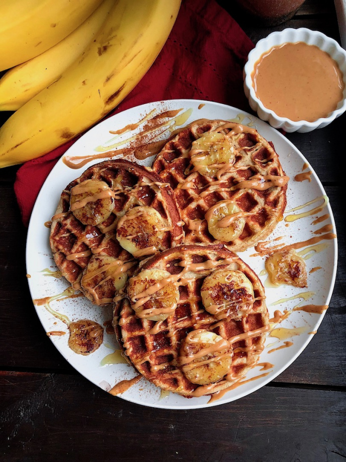 paleo waffles on a white plate with peanut butter and bananas on top 