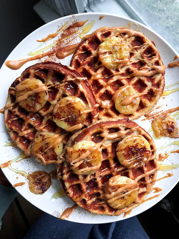 paleo waffles on a white plate with peanut butter and bananas on top