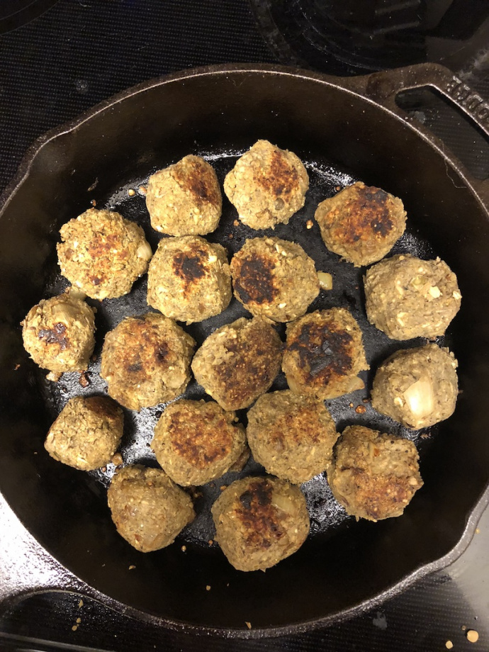 vegan meatballs in a red sauce in a cast iron pan