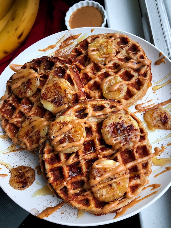 paleo waffles on a white plate with peanut butter and bananas on top