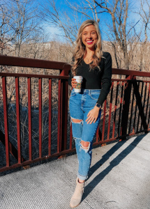 girl in black top and blue jeans with coffee