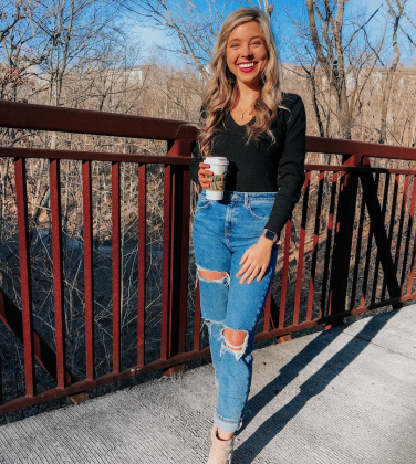 girl in black top and blue jeans with coffee