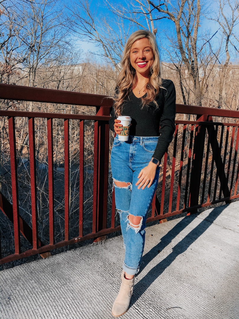 girl in black top and blue jeans with coffee